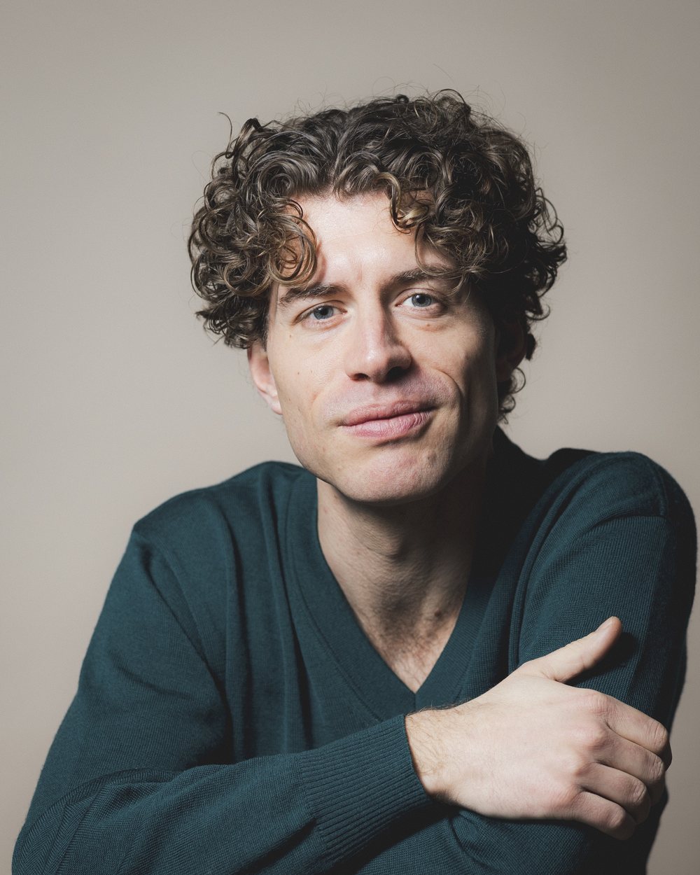 Maximilian Vogler, lyrischer Tenor und Gesangslehrer in Berlin, im dunkelgrünen Pullover vor hellem Hintergrund